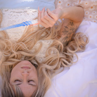 fairy lying down with blond hair with tattoo holding blue and white wand with white opal crystals