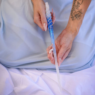fairy kneeling down with tattoo holding blue and white wand with white opal crystals