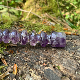 A unique handmade magic wand made with real purple amethyst crystal chips, in the Orbit  Design. 

The detail of the handle of the wand is shown with a mossy log in a woodland. 
