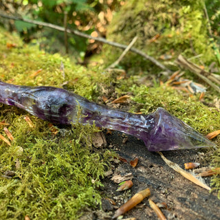 A unique handmade magic wand made with real purple amethyst crystal chips, in the Stiletto  Design. 

The detail of the pointed base of the wand is on a moss covered log in a woodland. 