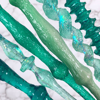 Close of of magic wands in various shades of green on a white background.