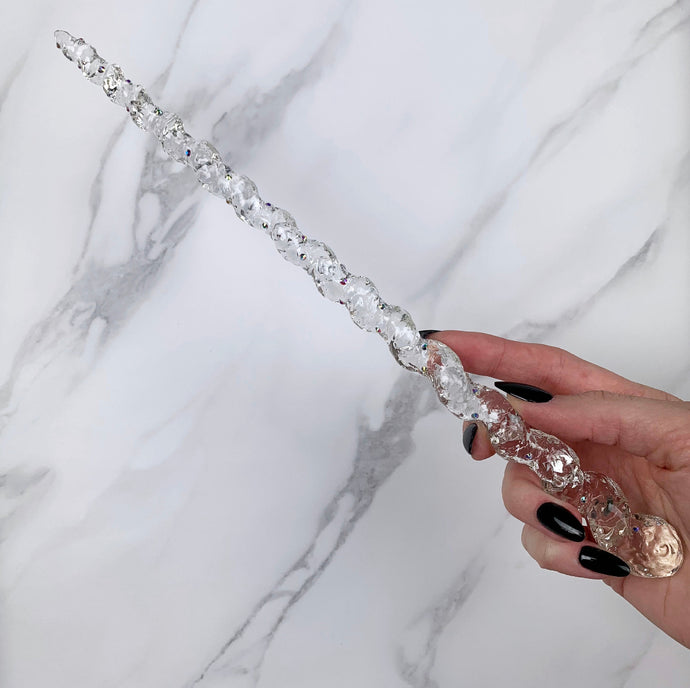 A stunning clear unicorn magic wand featuring a delicate, translucent design with iridescent shimmering accents. The wand has a gracefully tapered shaft that sparkles in light, showcasing its intricate craftsmanship. Perfect for fantasy collectors, this wand embodies elegance and enchantment, making it a prized addition to any magical assortment.