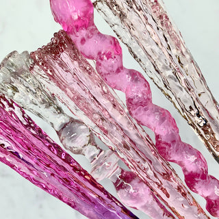 Close of of magic wands in various shades of pink on a white background.