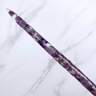 A unique handmade magic wand made with real purple amethyst crystal chips, in the Orbit  Design. 

The detail of the shaft of the wand is on a white marbled background. 