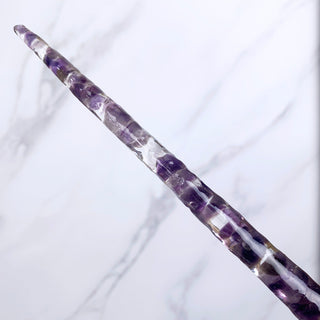 A unique handmade magic wand made with real purple amethyst crystal chips, in the Star  Design. 

The detail of the tip of the wand is on a white marbled background. 