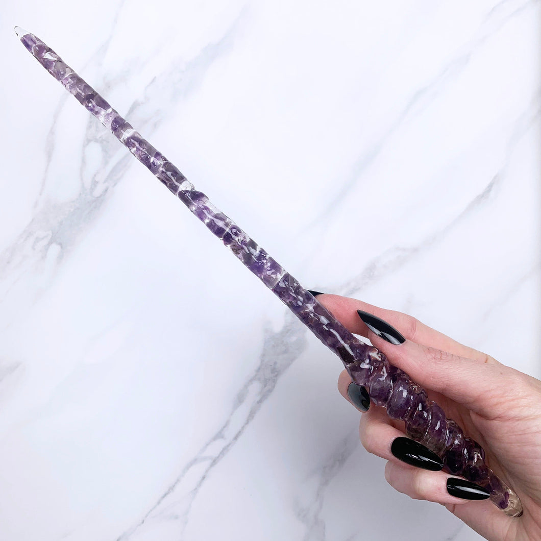 A stunning handcrafted Twist magic wand made with shimmering amethyst chips, showcasing a blend of purple hues. The wand has a gracefully tapered shaft that sparkles in light, showcasing its intricate craftsmanship. Perfect for fantasy collectors, this wand embodies elegance and enchantment, making it a prized addition to any magical assortment.