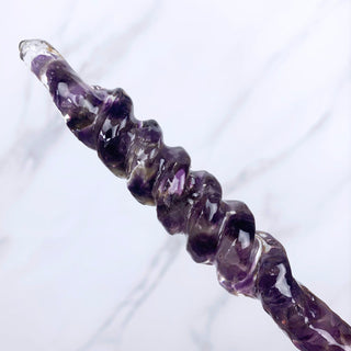 A unique handmade magic wand made with real purple amethyst crystal chips, in the Twist  Design. 

The detail of the twisted handle is on a white marbled background.