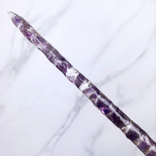 A unique handmade magic wand made with real purple amethyst crystal chips, in the Twist  Design. 

The detail of the tip of the wand is on a white marbled background. 