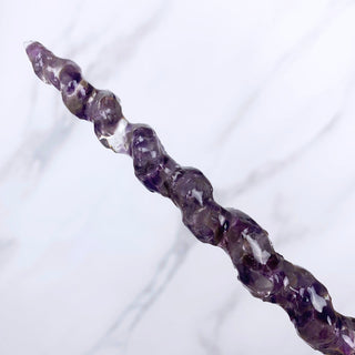 A unique handmade magic wand made with real purple amethyst crystal chips, in the Unicorn  Design. 

The detail of the spiral tip of the wand is on  a white marbled background.