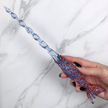 Charger l&#39;image dans la galerie, A stunning blue and orange Mermaid inspired magic wand featuring a delicate, translucent design with iridescent shimmering accents. The wand has a beautiful fishtail shaped base with a swirling shaft that sparkles in light, showcasing its intricate craftsmanship. Perfect for fantasy collectors, this wand embodies elegance and enchantment, making it a prized addition to any magical assortment.

