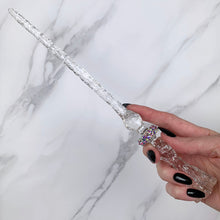 Load image into Gallery viewer, A stunning clear Flora magic wand featuring a delicate, translucent design with iridescent shimmering accents. The wand has a beautiful flower shaped base with a narrow shaft that sparkles in light, showcasing its intricate craftsmanship. Perfect for fantasy collectors, this wand embodies elegance and enchantment, making it a prized addition to any magical assortment.
