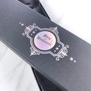 Black wand  box with  a holographic 'House of Wandcraft' branding on a white background close ip