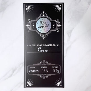 Decorative wand certificate with personalisation and holographic logo label with 'House of Wandcraft' branding on a white background
