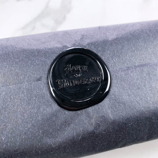 Close up of black wax seal stamp with 'House of Wandcraft' logo